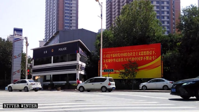Un commissariat de police, des caméras de surveillance et une grande affiche de propagande à Urumqi.