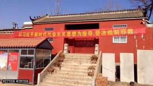 Une banderole sur laquelle est écrit « Résistez résolument aux xie jiao, et laissez-vous guider par la pensée de Xi Jinping sur le socialisme pour une nouvelle ère » est accrochée devant le temple de Beigongzhuang.