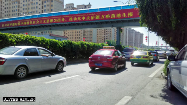 Le slogan d’une affiche de propagande à Urumqi au Xinjiang : « Promouvoir la pleine mise en œuvre de la stratégie du Comité central du Parti pour l’administration du Xinjiang », guidée par la pensée de Xi Jinping.