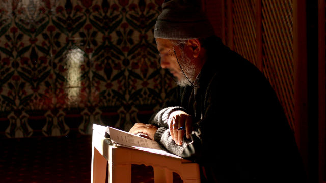 Un musulman âgé lisant le Coran