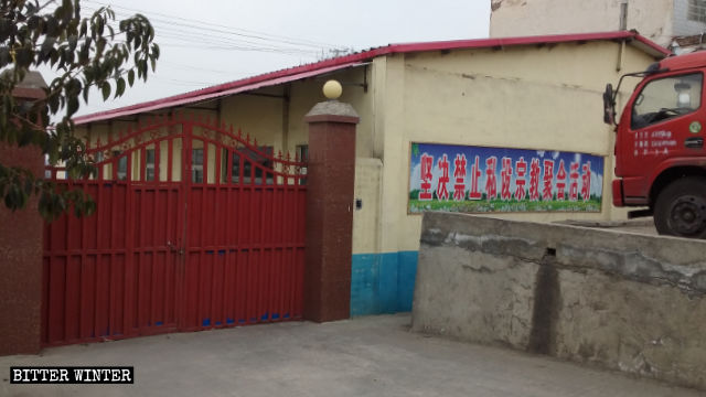 Une banderole sur laquelle est écrit « Activités et rassemblements religieux privés strictement interdits » a été accrochée sur le mur extérieur du lieu de rassemblement des Trois-Autonomies dans le village de Lugou.