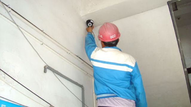 Un ouvrier installant une caméra de surveillance.