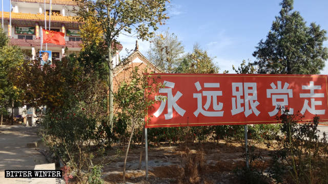 Devant le temple de Tianyi, il y a un panneau sur lequel est inscrit « Suivre le Parti à jamais »