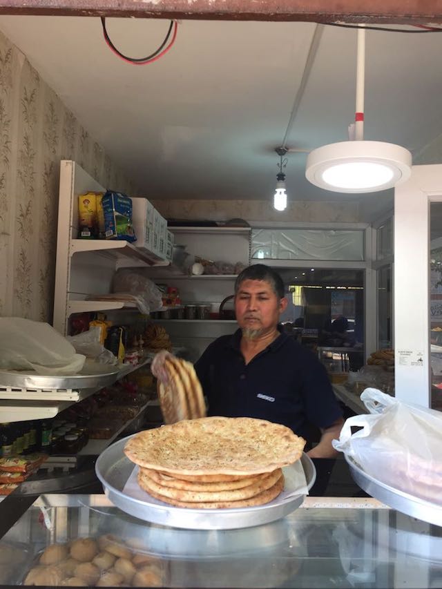Ce boulanger de Kashgar expose fièrement son pain « naan » tout chaud sorti du four « Tandoor ».