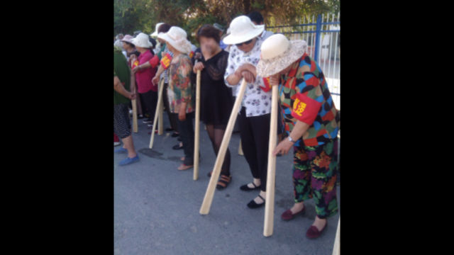 Des habitants d’une localité du Xinjiang tenant des bâtons pendant des « exercices de lutte contre le terrorisme »
