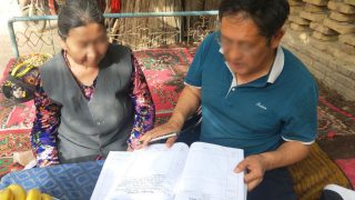 Un fonctionnaire du Xinjiang demande à une femme âgée de lire les documents.
