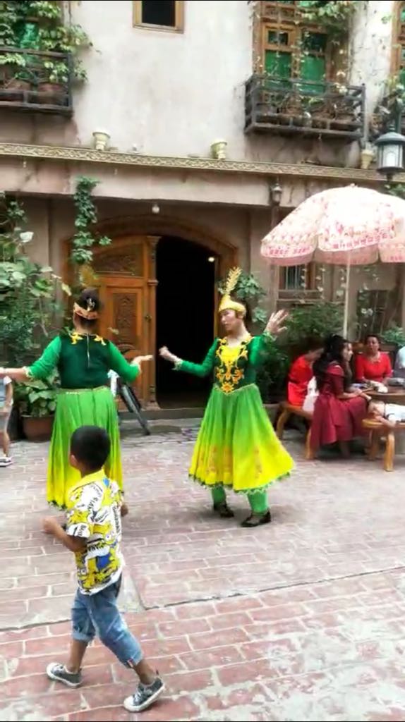 L’air très malheureux, les filles ouïghoures sont obligées de danser pour les touristes han à Kashgar.
