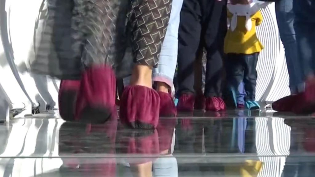 Les touristes portent des couvre-chaussures lorsqu’ils traversent le pont sur du verre spécialement conçu pour « se briser » et « éclater » sous leurs pieds.