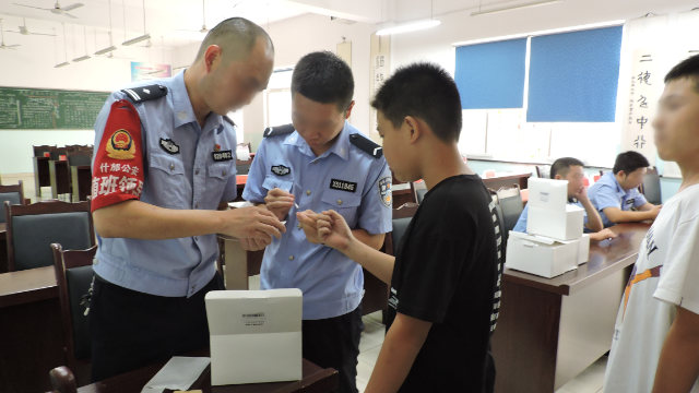 Des agents du Bureau de la sécurité publique de la ville de Shifang, dans le Sichuan, recueillent des échantillons d’ADN sur des collégiens.