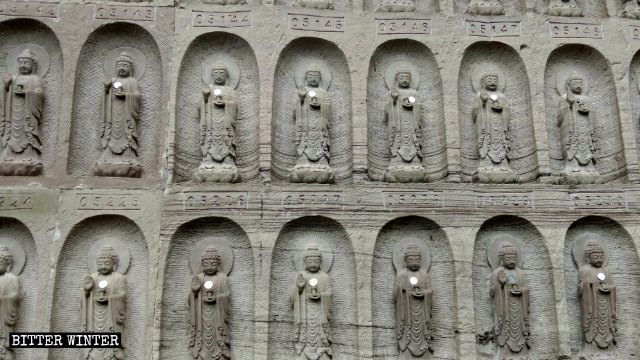 Gros plan sur les statuettes de Bouddha sculptées dans les murs de la falaise.