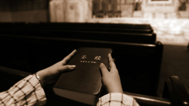 Une croyant tenant une bible, qui est toujours confisquée par la police lors des perquisitions des églises.