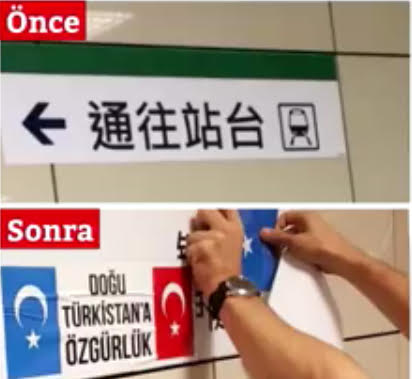 En-dessous du panneau en mandarin indiquant la direction du quai du tramway, un sympathisant turc accroche les drapeaux du Turkestan oriental et de la Turquie avec du ruban adhésif.